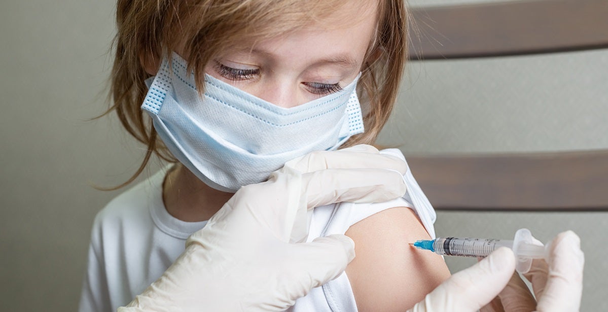 Public health nurse givving vacing to caucasian girl in a medical mask